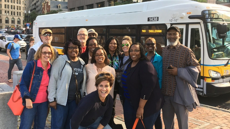 A group of educators posing outside of an MBTA bus with Dr. Katie Novak