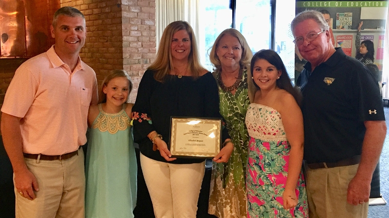 Liz Berquist standing with her family holding an Education Award
