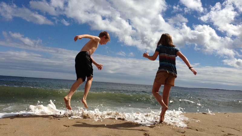 A photo of author Allison Posey's children playing in the surf at the beach.